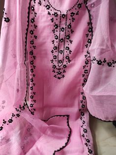 a pink dress with black beads on it