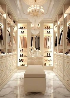 an elegant walk in closet with chandelier and shoes on the shelves, all white