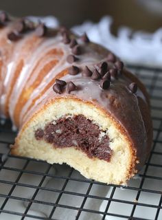 a half eaten chocolate covered doughnut on a cooling rack