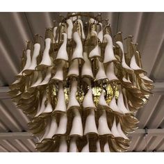 a chandelier with white and gold lights hanging from it's sides in a room