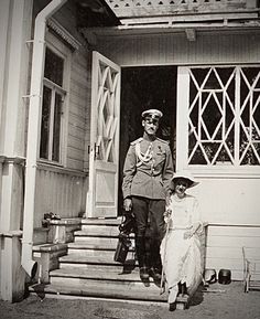 an old black and white photo of two people in front of a house with the door open