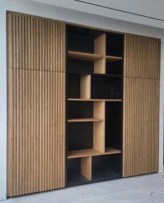 an open closet with wooden shelves and sliding doors on the outside, in front of a white wall