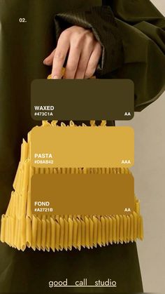 a person in a green coat holding some food and color swatches on their hands