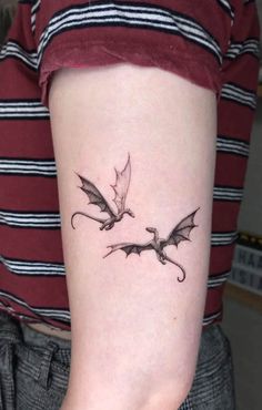 a woman with a tattoo on her arm that has two small dragon tattoos on it