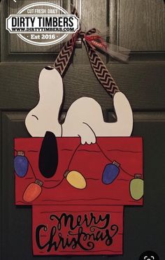 a door hanger with a snoopy christmas sign hanging from it's side