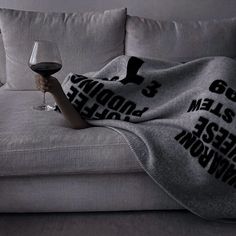 a couch covered with a blanket and a glass of wine