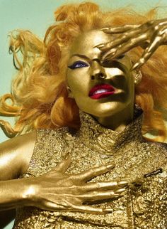 a woman with golden makeup and hands on her head