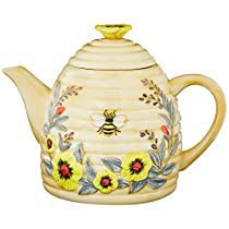 a ceramic tea pot decorated with flowers and a bee