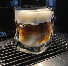 a glass filled with liquid sitting on top of a grill