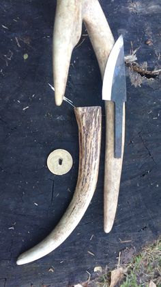 two knives are laying next to each other on a piece of wood that has been cut in half