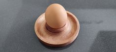 an egg is sitting on top of a wooden stand with a black surface behind it