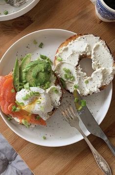 a white plate topped with a bagel covered in cream cheese and veggies