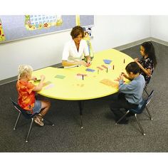 a group of children sitting around a yellow table