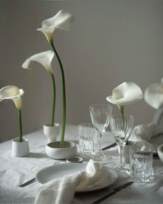 the table is set with white dishes and flowers