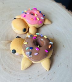 two donuts with sprinkles are sitting on a wooden plate next to each other