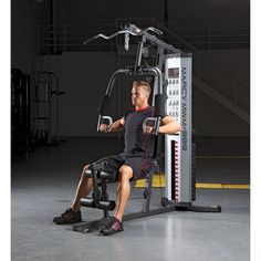 a man sitting on a bench in front of a gym machine with an arm curl