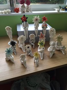 a collection of ceramic flowers sitting on top of a wooden table next to a window