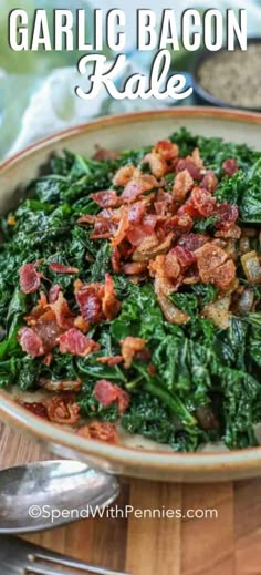 a bowl filled with spinach and bacon on top of a wooden table next to silverware