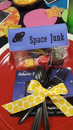 a red plate topped with plastic utensils next to a space junk sign and fork