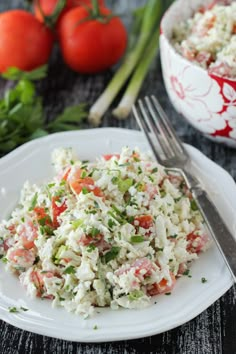 a white plate topped with salad next to a bowl of tomatoes and celery