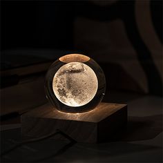 an illuminated glass ball sitting on top of a wooden block in the middle of a dark room