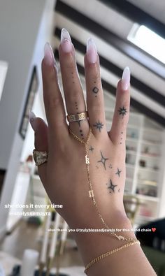 a woman's hand with tattoos on her fingers and two rings around her wrist