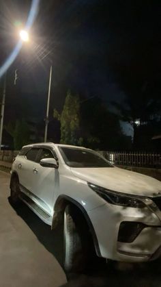 a white suv is parked on the street at night