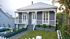 a grey house with white balconies on the porch