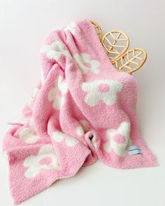 a pink and white blanket with hearts on it next to a gold brooch pin