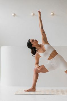 a woman standing on one leg in a yoga pose with her arms up and legs crossed