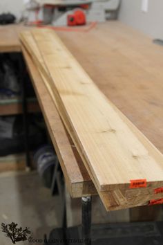 a close up of a wooden table with some orange tape on it's edge