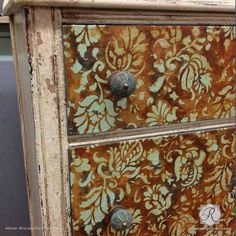 an old dresser has been painted with gold and orange floral designs on it's drawers