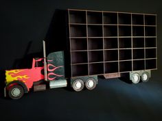 a wooden toy truck with flames painted on it's side, next to a bookcase