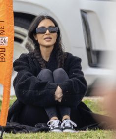 a woman sitting on the ground next to an orange flag with words written on it