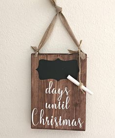 a wooden sign that says days until christmas hanging on a wall with a chalkboard