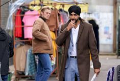 a man in a turban walks down the street while talking on his cell phone