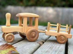 a wooden toy train sitting on top of a wooden table next to an autumn leaf