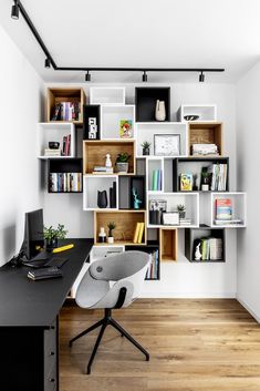 a desk with a computer and bookshelves in the corner on top of it