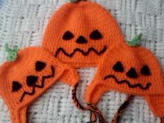 two crocheted pumpkin hats with faces on them