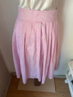 "This gorgeous button down pink and white skirt is so pretty! The composition is 50% polyester and 50% cotton. Would be perfect paired with cowboy boots and a prairie shirt, or with a white blouse tucked in and leather huaraches. Our best guess is that it is a women's medium to large, it is marked a size 11/12. But please check the measurements given below to ensure a proper fit. It was made in the early 1980's in the USA by Avon Fashions, and buttons completely down. It is in good condition wit Spring Striped Flared Skirt, Pink Lined Skirt For Daywear, Spring Relaxed Skirt With Striped Hem, Relaxed Skirt With Striped Hem For Spring, Striped Pleated Knee-length Skirt, Preppy Pink Cotton Skirt, Spring Striped Pleated Skirt, Summer Striped Pleated Skirt, Pleated Striped Skirt For Summer