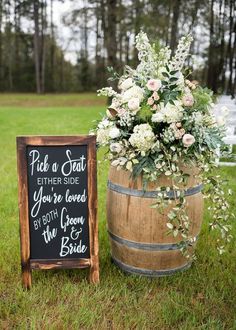 a wooden barrel with a chalkboard sign next to it and flowers in the middle