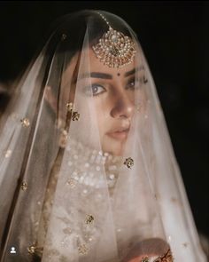 a woman wearing a veil with gold beads on her head and in the background is an image of a bride's face