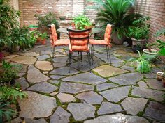 an outdoor patio with chairs and tables surrounded by plants