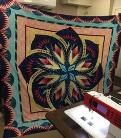 a quilt hanging on the wall next to a sewing machine