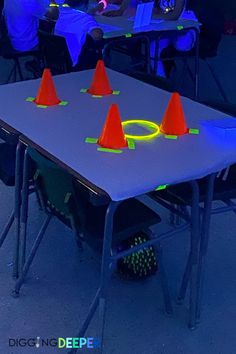 a group of people sitting around a table with orange cones on top of it in front of them