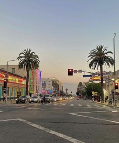 an intersection with cars and palm trees at dusk