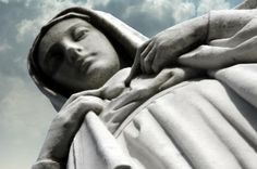 a close up of a statue with clouds in the background