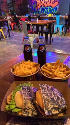 two trays filled with sandwiches and fries sitting on top of a table in a restaurant