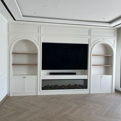 an empty living room with built in shelves and a flat screen tv