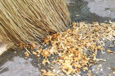 a pile of wood shavings sitting on top of a cement floor next to a brush